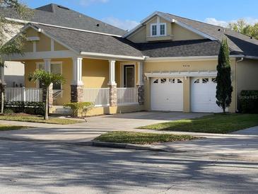 Charming home with two-car garage, covered porch, stone accents, and manicured lawn at 9238 Kensington Row Ct, Orlando, FL 32827