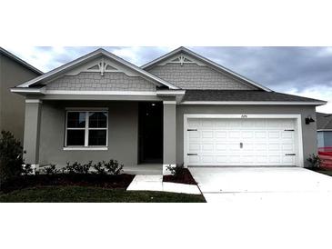 Gray house with white garage door and landscaping at 7175 Painted Bunting Way, Saint Cloud, FL 34773