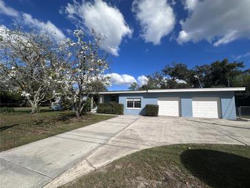 Charming home featuring a well-maintained lawn, a three-car garage, and a flowering tree in the front yard at 1951 S Crystal Lake Dr, Orlando, FL 32806