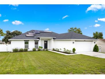 Charming single-story home with a well-manicured lawn, solar panels, and a two-car garage at 1302 Belmar Ter, Deltona, FL 32725