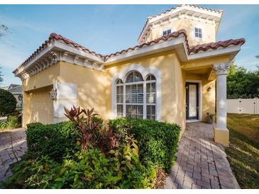 Two-story house with yellow exterior, landscaped yard, and brick driveway at 8162 Via Bella Notte, Orlando, FL 32836