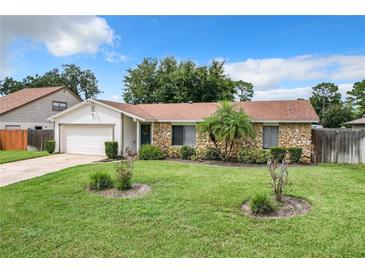 Ranch style home with stone facade, mature landscaping, and a two-car garage at 104 E Berkshire Cir, Longwood, FL 32779