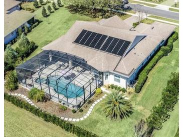 Stunning aerial view of home with pool, screened-in lanai, solar panels and lush landscaping at 5509 Meadow Hill Loop, Lady Lake, FL 32159