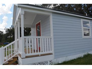 Newly built home with gray siding, white porch, and red door at 575 2Nd St, Oviedo, FL 32765