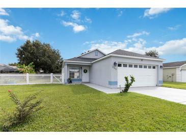 Cute one-story house with a white picket fence and a two-car garage at 805 Nelson Dr, Kissimmee, FL 34758