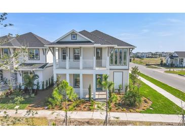Two-story home featuring a covered porch, balcony, and lush landscaping at 9982 Fiddley Aly, Orlando, FL 32827