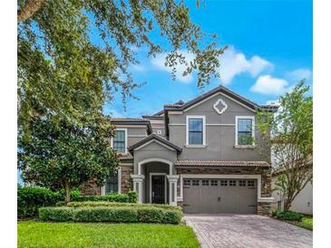 Charming two-story home with stone accents, a well-manicured lawn, and a two-car garage at 1427 Rolling Fairway Dr, Davenport, FL 33896