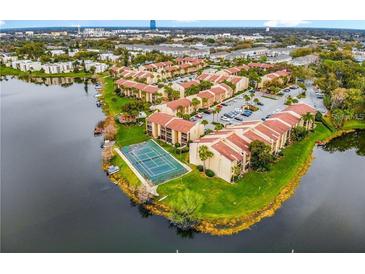 Aerial view of lakefront condos with a tennis court, mature landscaping and ample parking at 588 Orange Dr # 131, Altamonte Springs, FL 32701
