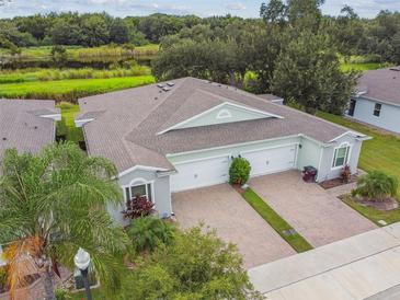 A villa showcasing a two-car garage with a brick driveway and a lush green landscape at 1862 Overcup Ave, Saint Cloud, FL 34771