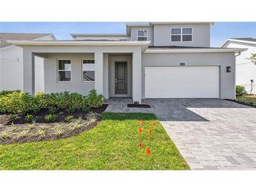 Contemporary home featuring a two-car garage, neutral tones, landscaped yard, and an inviting covered front entry at 1694 Pinecliff Dr, Apopka, FL 32703