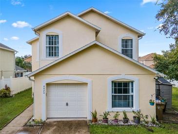 Two-story house with a white garage door and landscaping at 4420 Hamlet Ct, Kissimmee, FL 34746