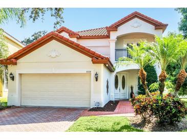 Two-story house with a red tile roof, attached garage, and lush landscaping at 8168 Via Bella Notte, Orlando, FL 32836