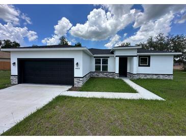 Charming single-story home with a black garage door, white stucco and well-manicured lawn at 442 Marion Oaks Crse, Ocala, FL 34473