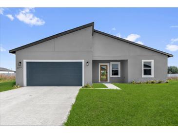 Modern gray home with a blue garage door, green lawn, and minimalist landscaping under a sunny blue sky at 4683 Sw 136Th St, Ocala, FL 34473