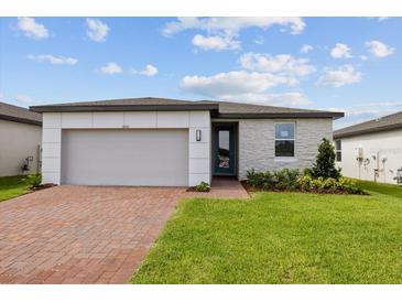 Brick front exterior of a single-story home with a two-car garage and landscaped lawn at 5161 Springrise Dr, Saint Cloud, FL 34772