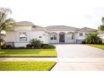 White two-story house with gray roof, paver driveway and landscaping at 1424 Olympic Club Blvd, Champions Gate, FL 33896