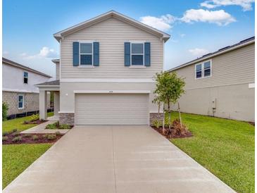 Two-story house with beige siding, two-car garage, and landscaping at 424 Wayland Dr, Haines City, FL 33844