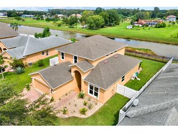 An aerial view of the charming tan home showcasing the landscape, and the tranquil water behind the property at 2685 Star Grass Cir, Kissimmee, FL 34746