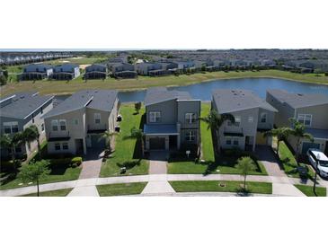 Modern two-story home with gray exterior, landscaped front yard, and pond views in a Primary-planned community at 8938 Cabot Cliffs Dr, Davenport, FL 33896