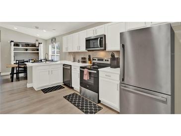 Modern kitchen featuring stainless steel appliances, white cabinetry, and wood flooring at 188 Ridgemont Ct, Davenport, FL 33896