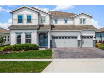 Charming two-story home with a three-car garage, neat landscaping and a manicured front lawn on a sunny day at 3198 Sailing Pier Ave, Winter Garden, FL 34787