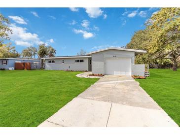 Charming single-story home with a well-manicured lawn and a private driveway leading to an attached garage at 5416 Milan Dr, Orlando, FL 32810