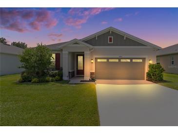 Charming single-Gathering home with a well-manicured lawn and two-car garage as seen at twilight at 10204 Spring Lake Dr, Clermont, FL 34711