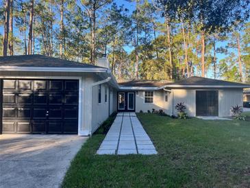 Charming single-story home with a manicured lawn and attached garage nestled among tall trees at 14315 Conifer Dr, Orlando, FL 32832