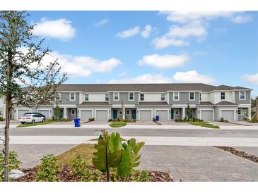 Row of modern townhomes with neutral paint, individual garages, and well-maintained landscaping at 203 River Front Way, Edgewater, FL 32141