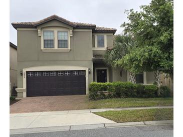 Two-story home featuring a dark-brown two-car garage, neutral paint, and meticulously manicured landscaping at 8844 Corcovado Dr, Kissimmee, FL 34747