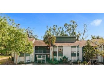 Exterior view of condo with trees, multiple balconies, and stairs to the second level, painted with cream and green trim at 2432 Lemon Tree Ln # B, Orlando, FL 32839