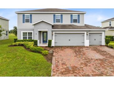 Charming two-story home featuring a three-car garage, blue shutters, landscaped yard, and a brick driveway at 4271 Tigris Dr, Apopka, FL 32712