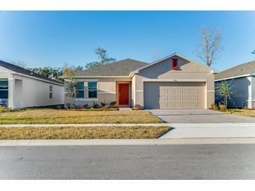 Charming single-story home with a well-manicured lawn, paved driveway, and a welcoming red front door at 345 River Front Way, Edgewater, FL 32141