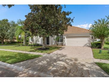 Charming single-story home with a tile roof, brick driveway, and a beautifully landscaped front yard at 11045 Belmere Isles Ct, Windermere, FL 34786