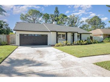 Charming ranch house with dark brown garage door and well-manicured lawn at 6341 Edge O Grove Cir, Orlando, FL 32819