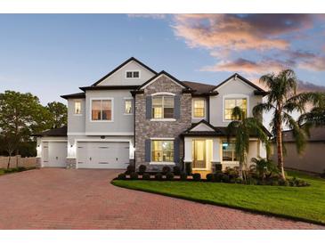 Charming two-story home with stone accents, a brick driveway, and lush landscaping, blending elegance and curb appeal at 13016 Shady Retreat Loop, Clermont, FL 34711