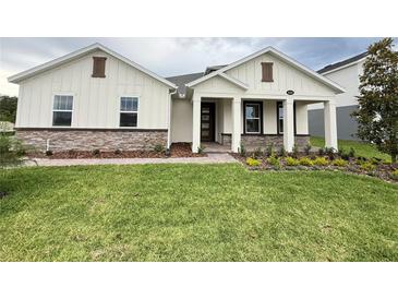 Charming single-Gathering home featuring stone accents, lush green lawn, and a welcoming front porch at 2564 Hawks Overlook Pl, Oviedo, FL 32765