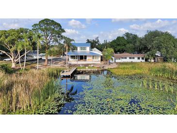 Beautiful waterfront home featuring a dock, a blue roof, and a charming outdoor patio, perfect for lakeside living at 1322 Susannah Blvd, Orlando, FL 32803