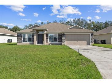 Charming single-story home featuring stone accents, attached two-car garage, and well-manicured lawn at 1928 Michigan Ct, Kissimmee, FL 34759