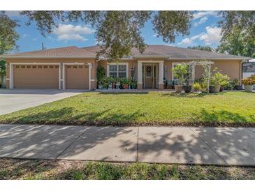 Tan house with three car garage and manicured lawn at 290 Thomas Dr, Casselberry, FL 32707