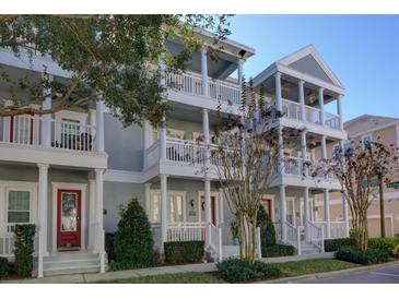 Charming townhome exterior with multiple balconies, white pillars, red doors, and well-maintained landscaping at 535 Crimson Ln, Winter Springs, FL 32708