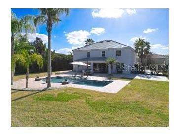 Backyard view of a private pool surrounded by lush greenery, a lounge area, and a well-manicured lawn at 10542 Wittenberg Way, Orlando, FL 32832
