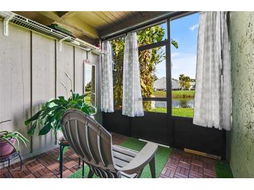 Serene screened porch featuring wood flooring, a comfortable chair, and views of the lush greenery and pond at 5783 Peregrine Ave # C07, Orlando, FL 32819
