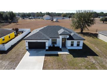 New construction home featuring a black garage door, modern landscaping, and a well-maintained front yard at 6208 Sw 129Th St, Ocala, FL 34473