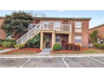 Inviting brick two-story condo building featuring landscaped grounds, a parking lot and stairwell access to upper level units at 476 Banyon Tree Cir # 104, Maitland, FL 32751