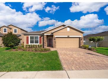 Tan house with red shutters, paver driveway, and landscaped lawn at 10063 Malmsbury Rd, Orlando, FL 32829