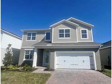 Two-story home featuring a brick driveway, a two-car garage and neutral-colored siding under a clear blue sky at 1169 Basalt Ln, Sanford, FL 32771