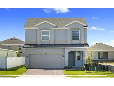 Charming two-story home with a gray exterior, brick paver driveway, and well-manicured front lawn at 7247 Rolling Leaf Rd, Groveland, FL 34736