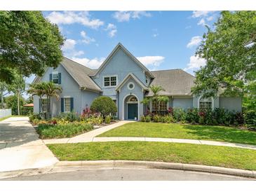 Charming home with a beautifully landscaped front yard, lush gardens, and a welcoming blue facade at 2523 Madron Ct, Orlando, FL 32806