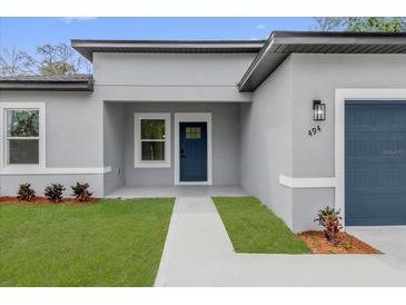 Charming home featuring a blue front door, manicured lawn, and fresh landscaping at 494 Marion Oaks Trl, Ocala, FL 34473
